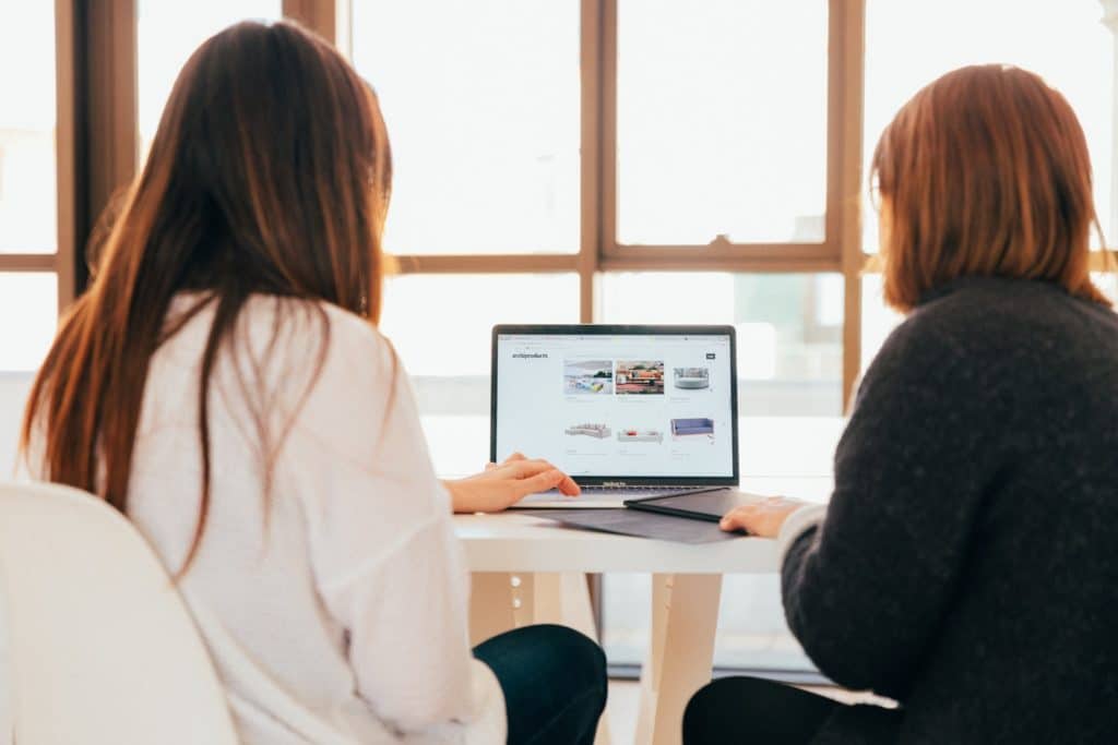 two women talking while looking at laptop computer as part of GDPR Compliance