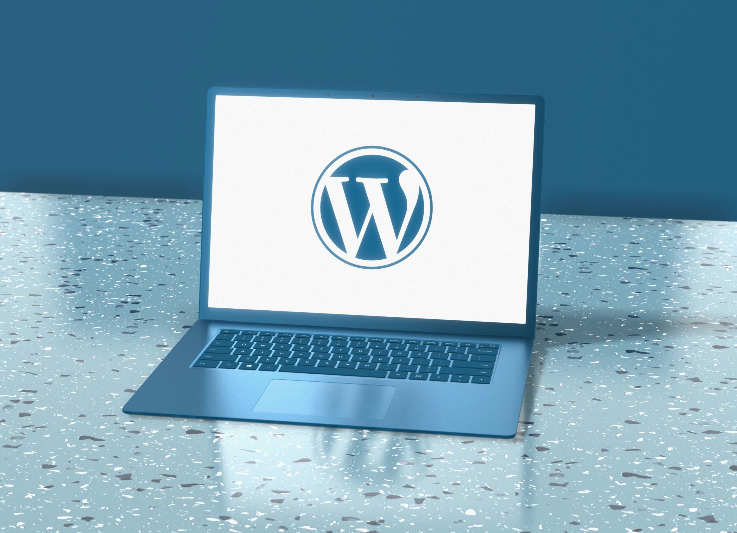 A laptop computer sitting on top of a table displaying the WordPress logo.